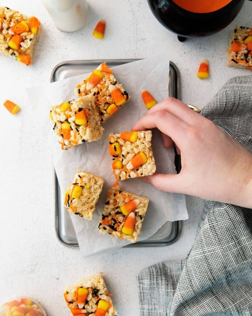 An overhead view of cut rice crispy treats decorated for Halloween on a piece of parchment paper.