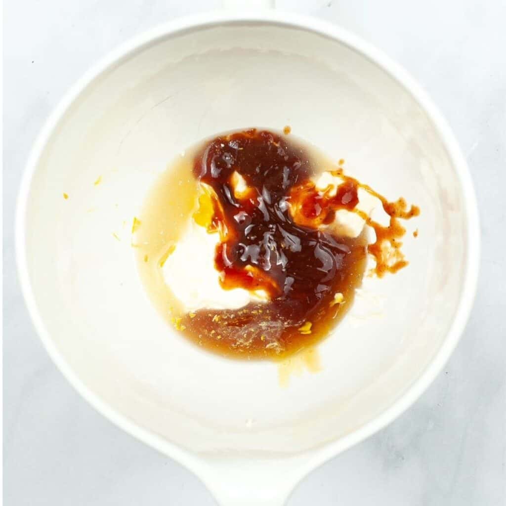 A white bowl with a mixture of honey, bbq sauce, and mayonnaise in the bowl.