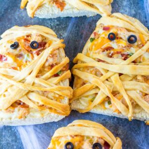 French bread pizza mummys on a blue linen napkin.