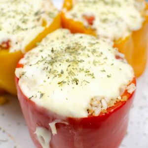 A side view of a red pepper stuffed with rice and topped with melted mozzarella.