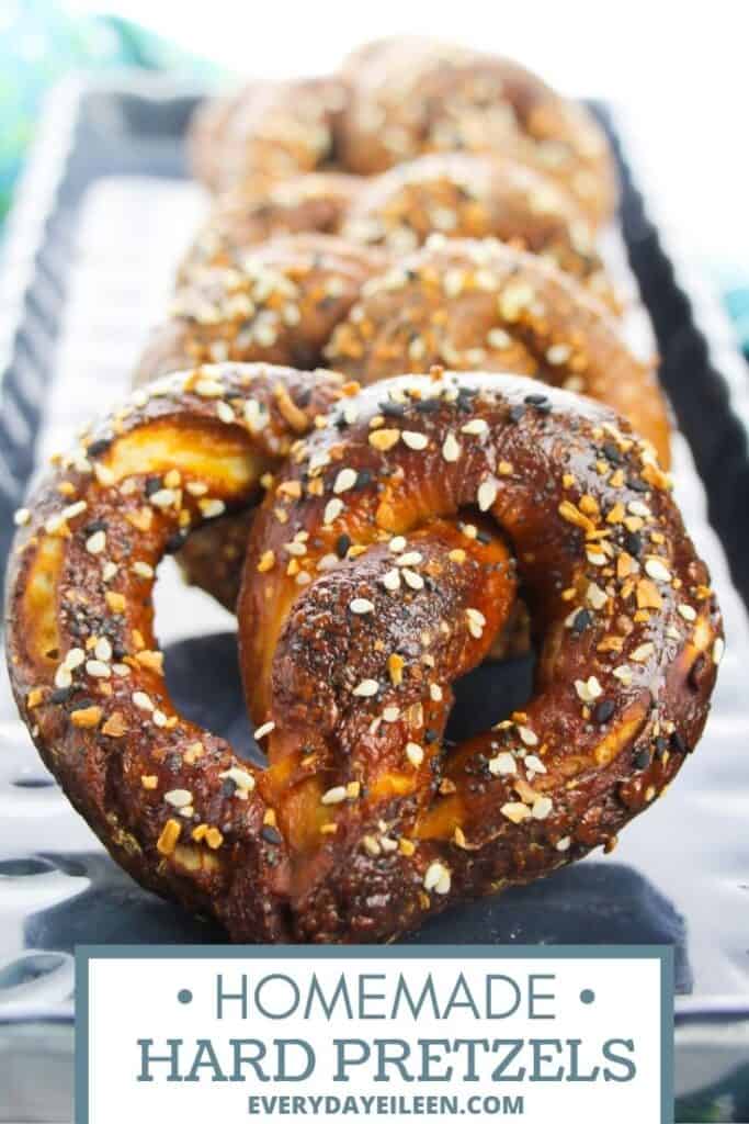 A group of hard pretzel with poppy seeds, black seeds on them lined up on a blue plate.