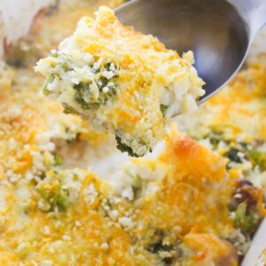 Broccoli rice and melted cheese on a spoon over the rice casserole dish.