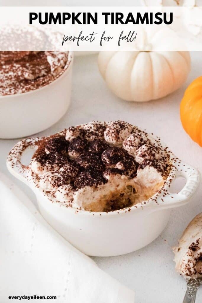 A white table topped with a white small ceramic crock with pumpkin tiramisu in it.