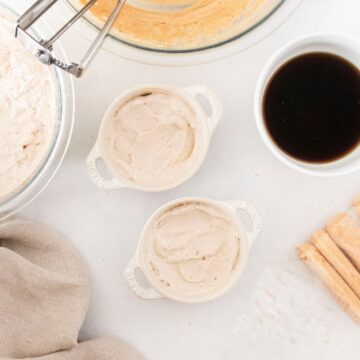 Two cocotte bowls with creamy pumpkin whip cream on top.