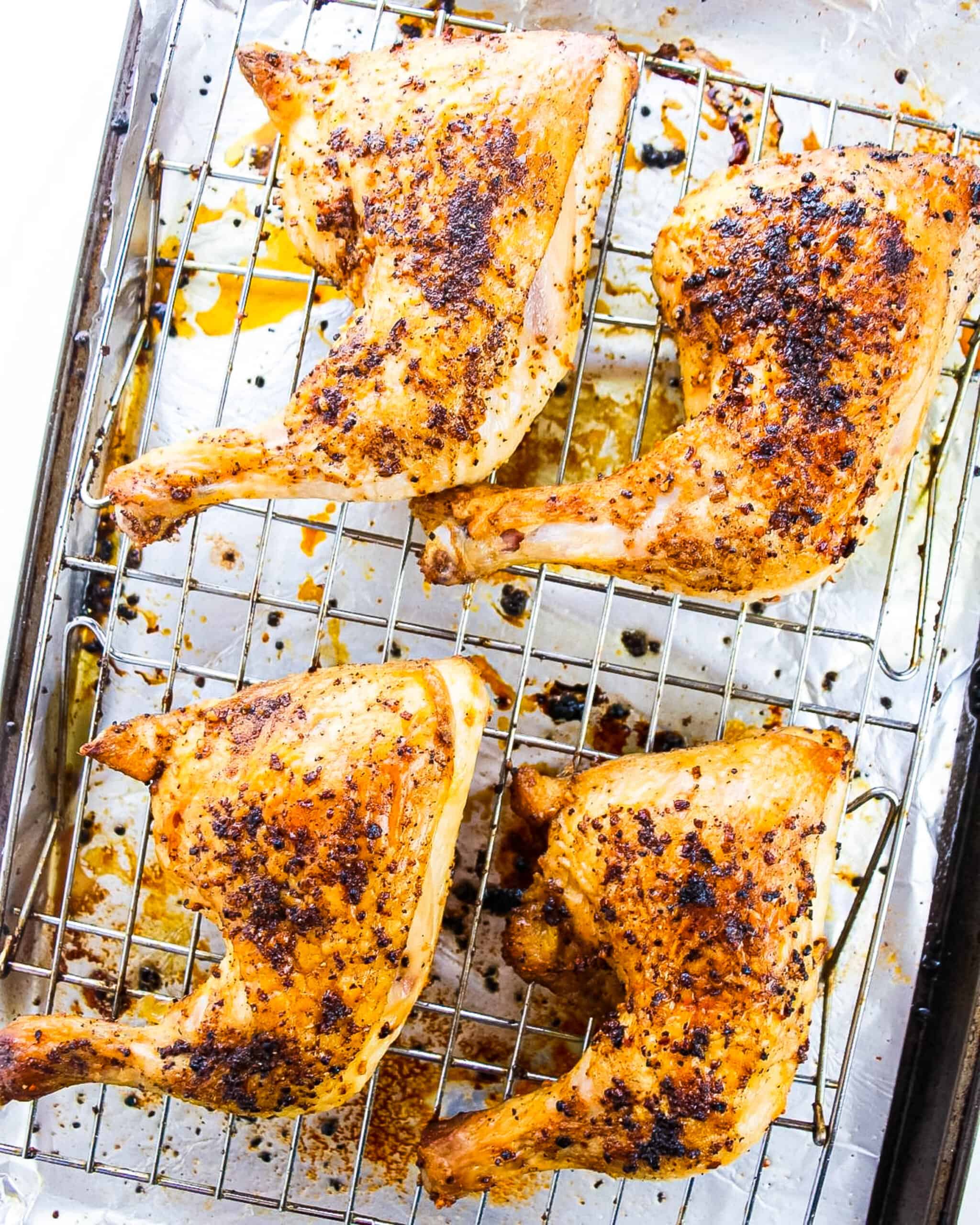 Chicken leg quarters baked on a wire rack.