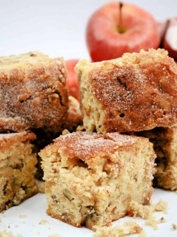 Slices of blondies with red apples behind them.