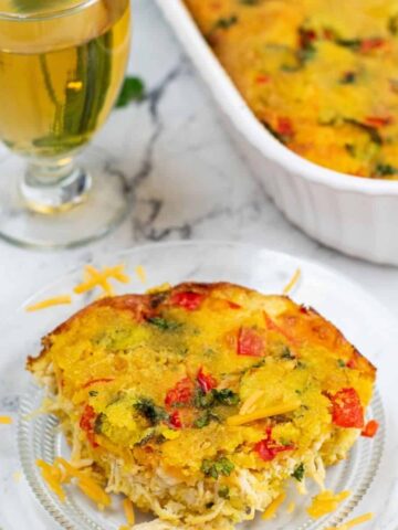 A glass plate with yellow cornbread, peppers, and chicken with the white casserole dish behind the plate.