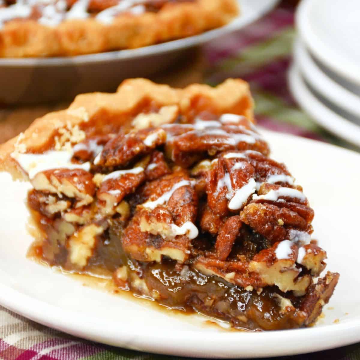 A slice of pie topped with pecans and a drizzle of white cream.