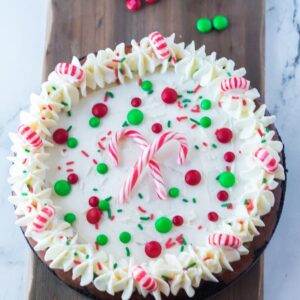 A christmas cheesecake topped with red and green m and ms and candy canes.