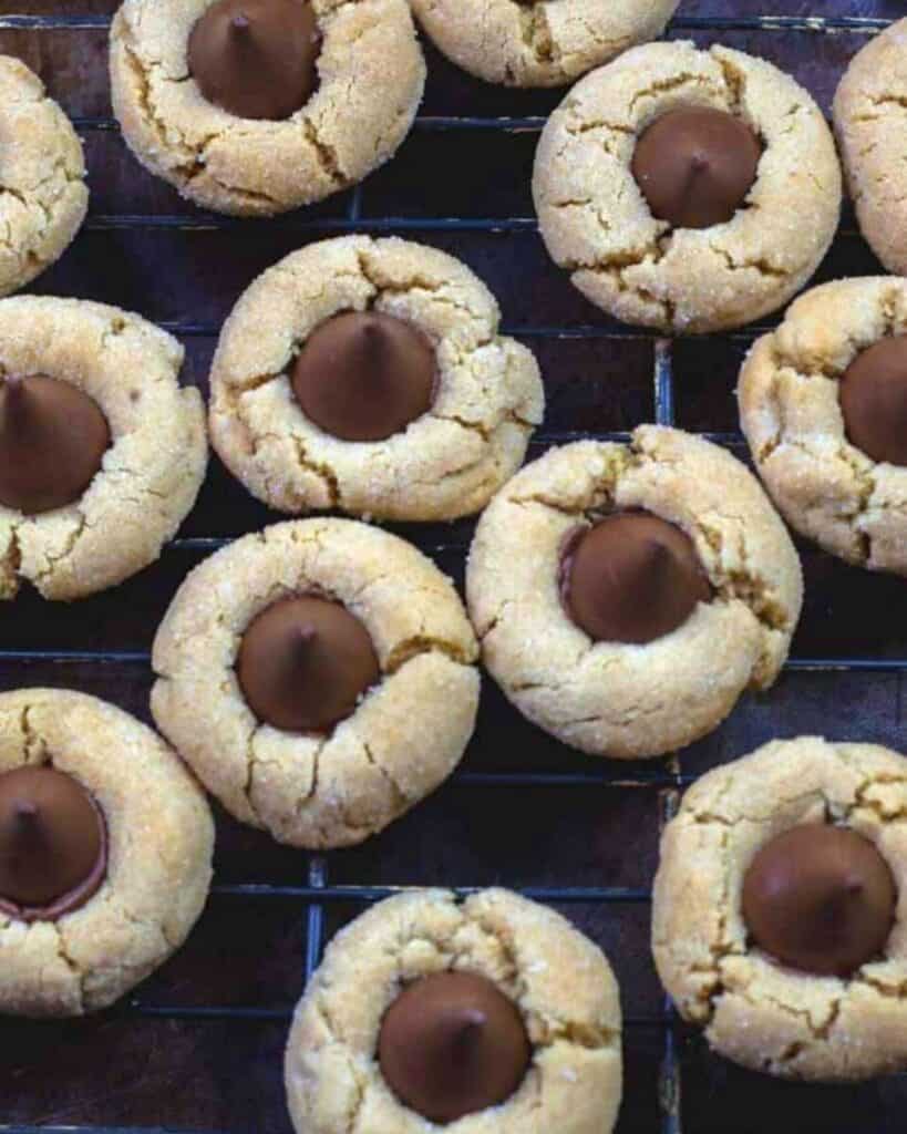 An overhead view of peanut butter cookies with a hershey kiss in the center of each cookie. 