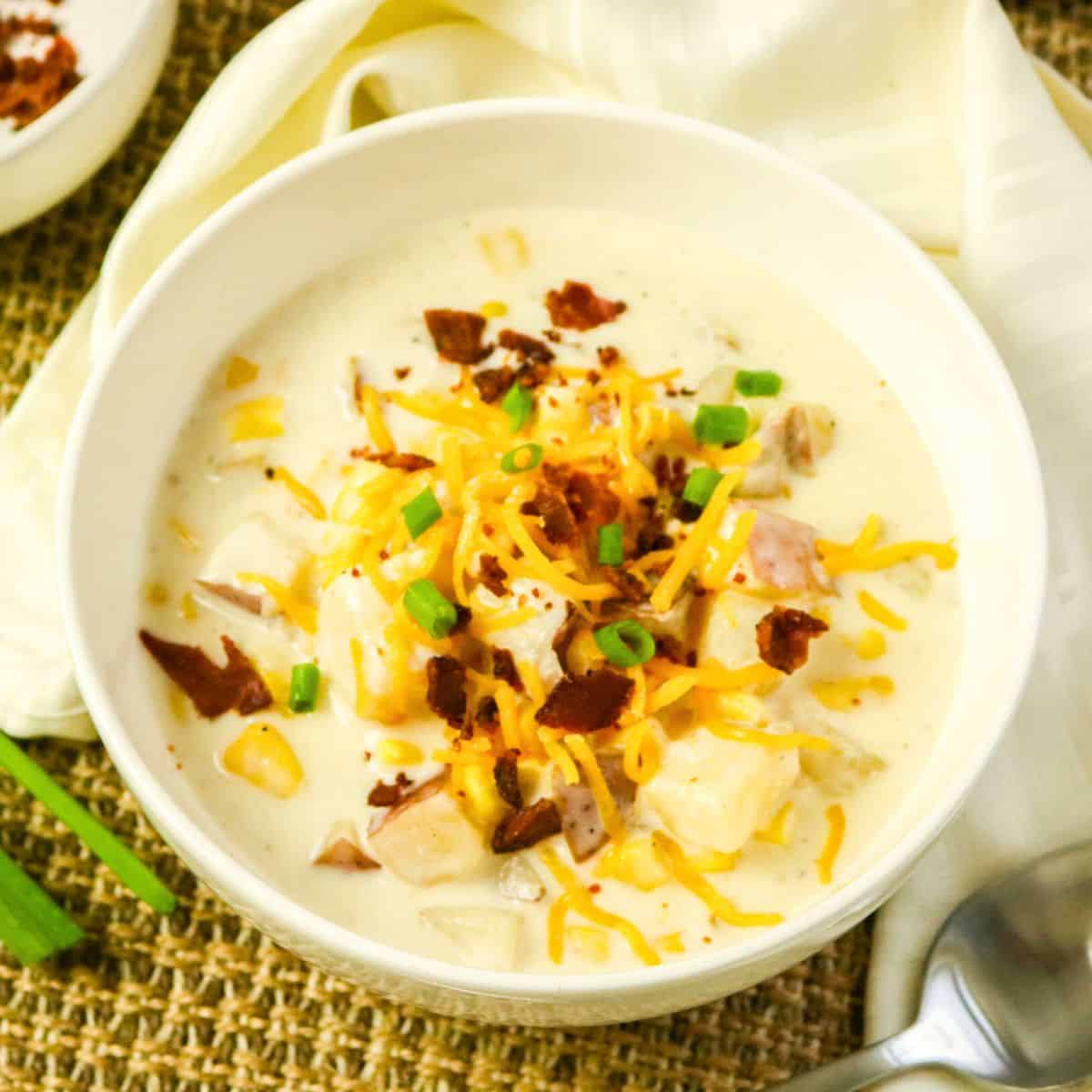 Slow Cooker Corn Chowder in a bowl topped with bacon and green onion.