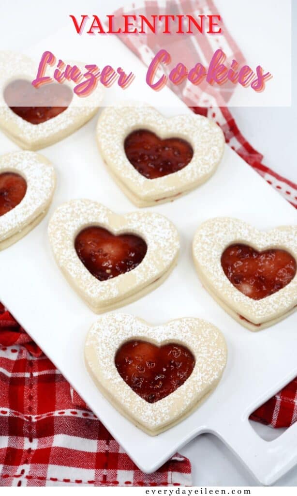 A white tray with heart shaped cookies on it with a red jam center.
