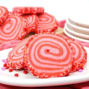 A white plate with pink and red swirled cookies on it.