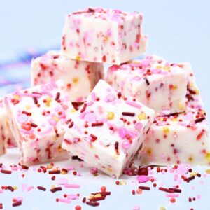 A group of light pink fudge with sprinkles throughout the fudge.