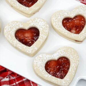 An overhead view of linzer tarts shaped into hearts with w red jam filling.