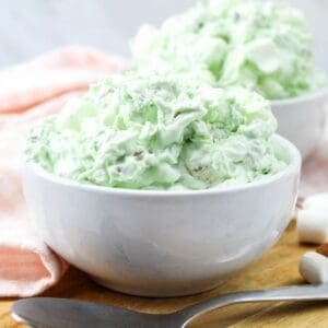 A white bowl of watergate salad with pistachio pudding, marshmallows, and pineapples.