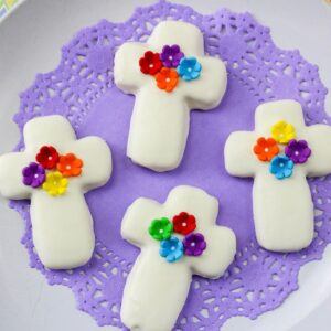 Cookies shaped as crosses on a purple lace felt on a white platter.