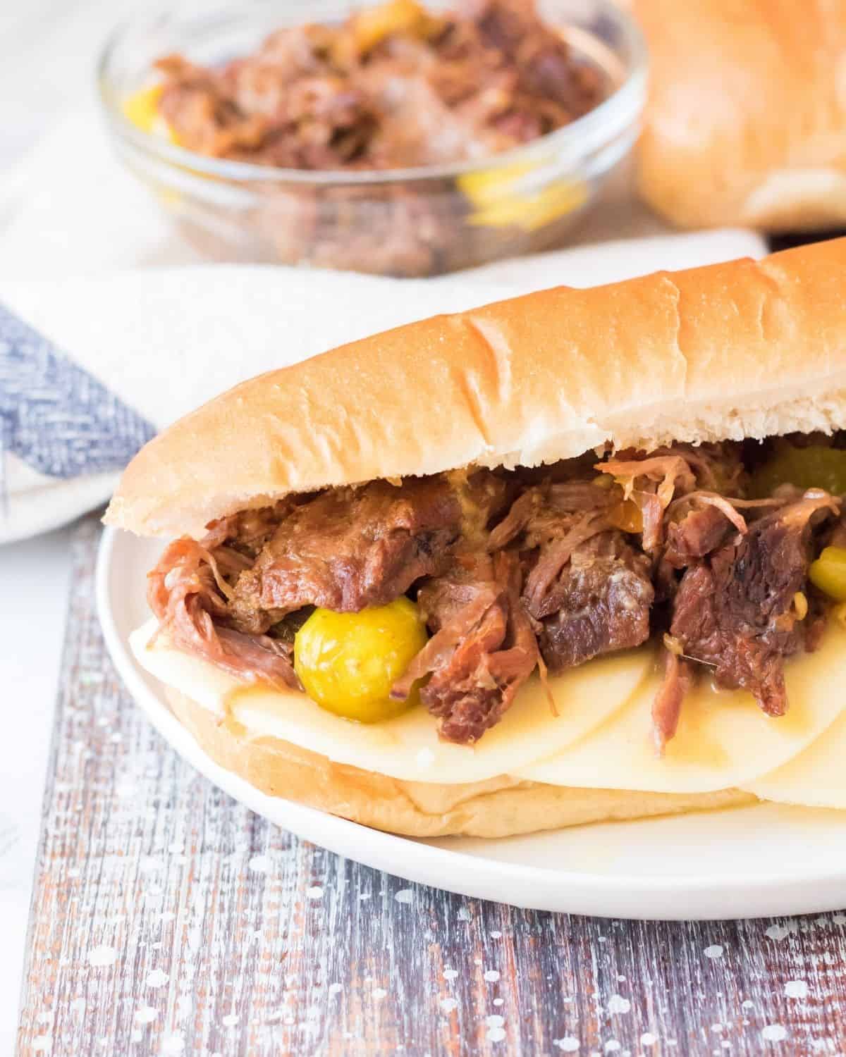 Slow cooker Italian beef made into a hoagie with pepperocini and provolone cheese.