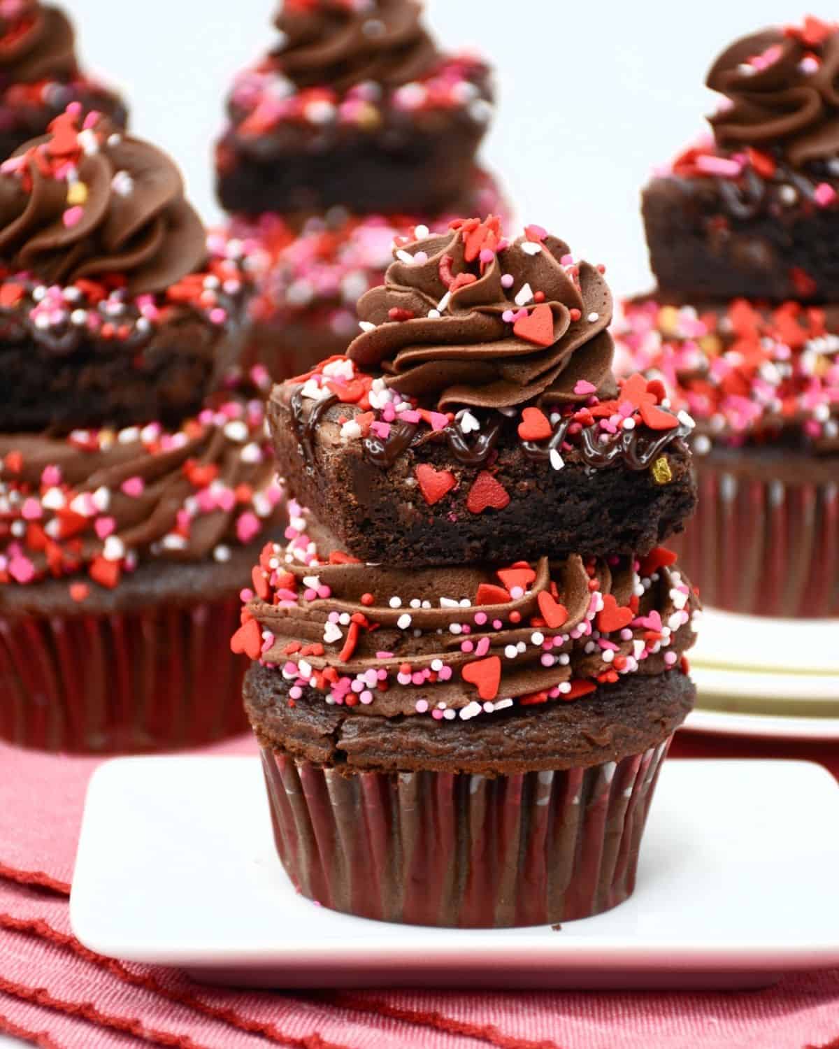 Valentines Day homemade cupcakes with chocolate frosting and sprinkles topped with a brown and more festive sprinkles.