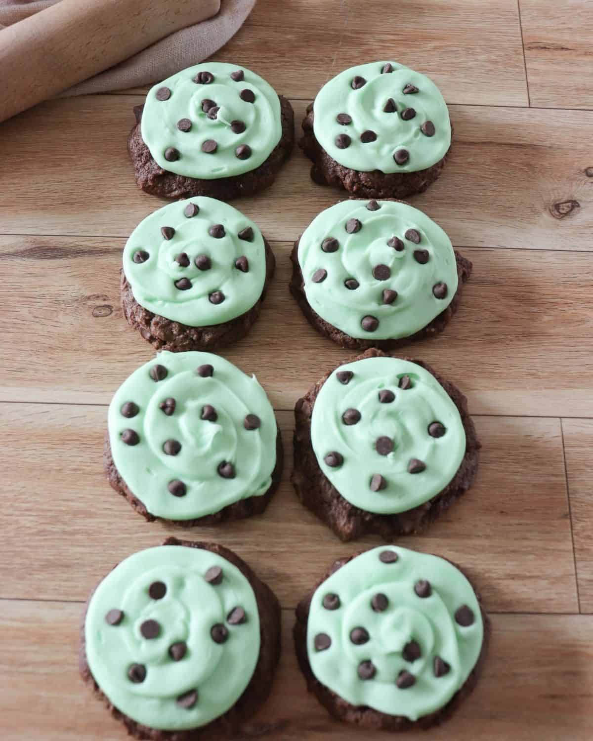 Chocolate cookies with a green frosting and small chocolate chips on top of the cookis.