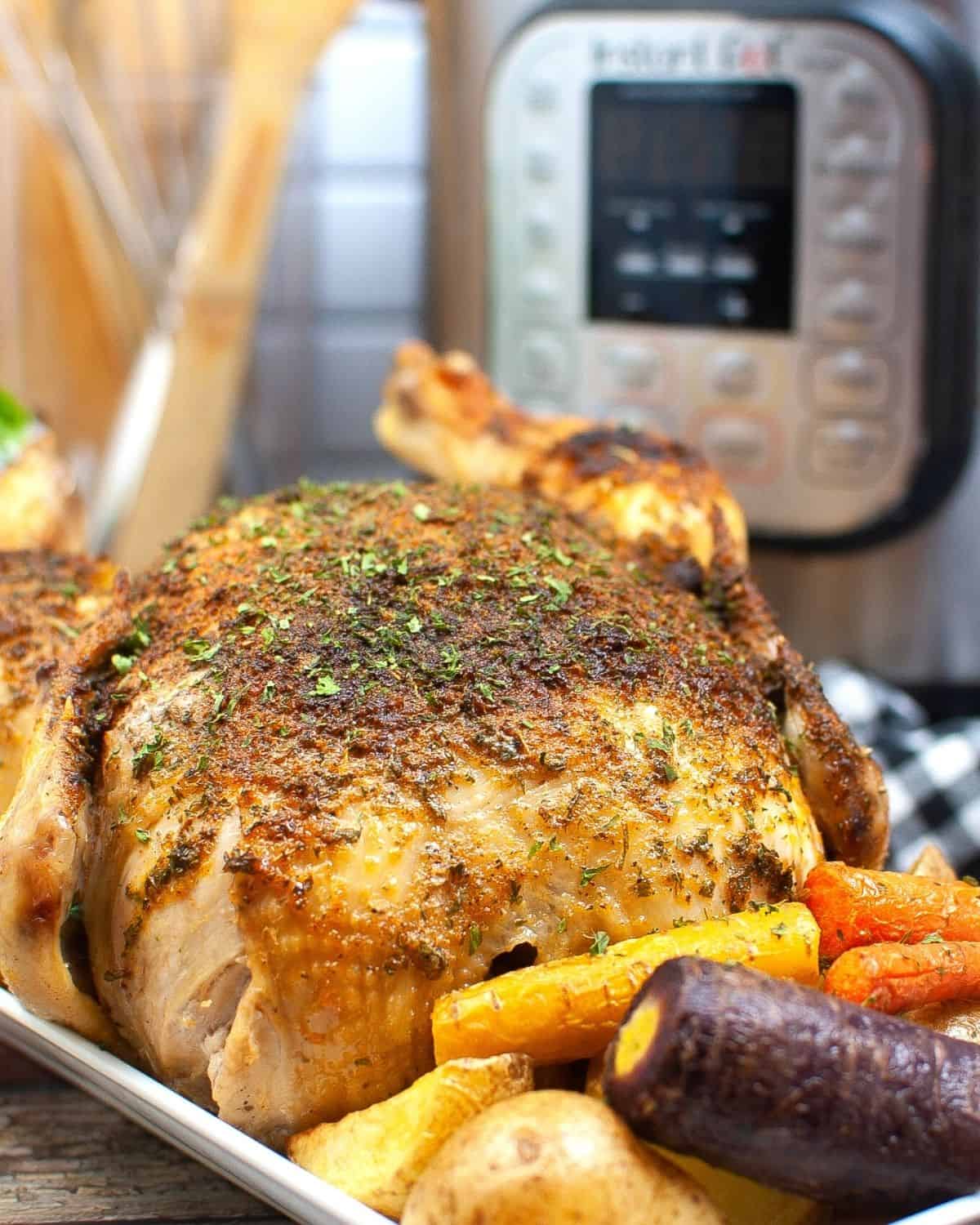 A roasted chicken that was made in the pressure cooker on a platter with carrots.