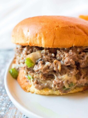 A white plate with a philly cheesesteak sloppy joe on the plate.