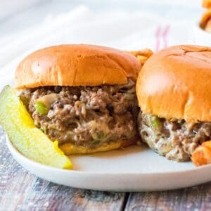 A ground beef sandwich with chopped peppers, mushrooms, and onions with cheese melted throughout on hamburger buns.