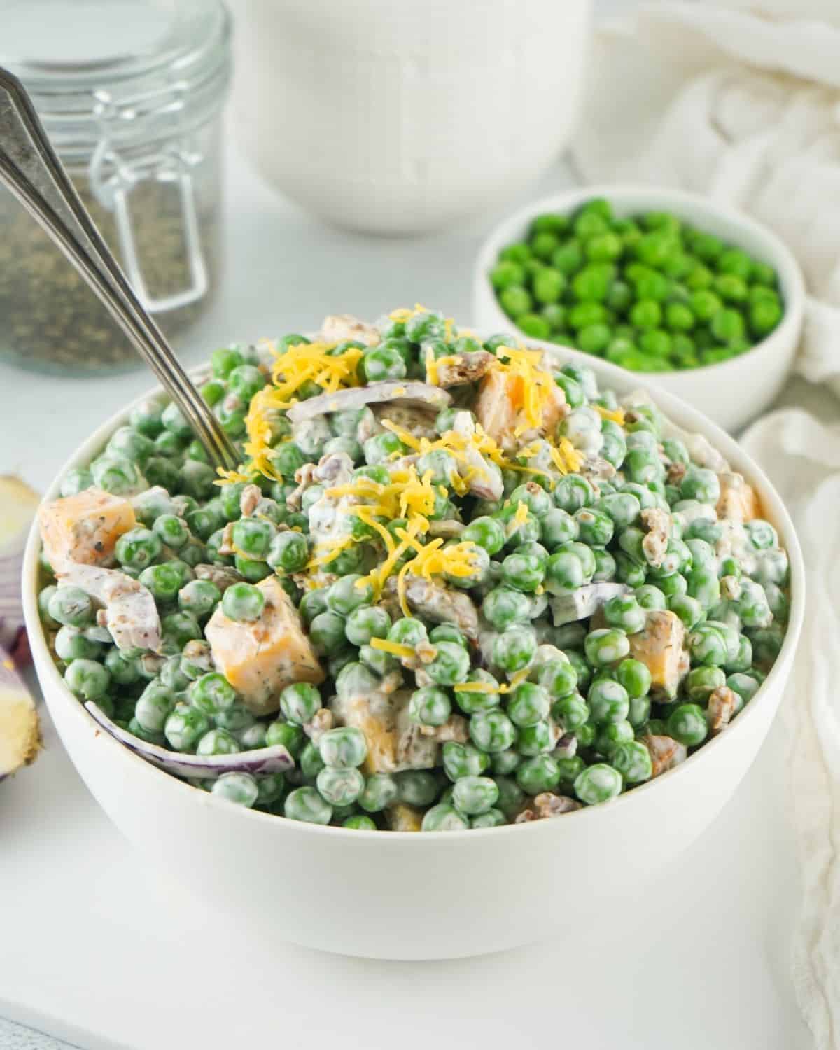 Bacon Pea Salad with cheese in a large white bowl. 