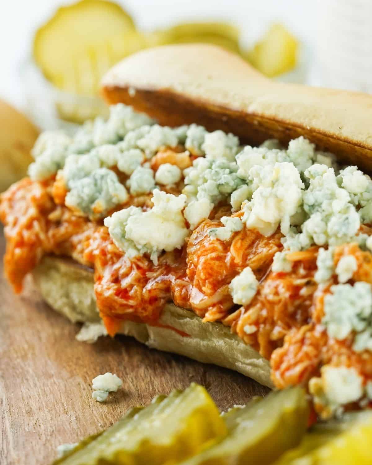 Crockpot Buffalo Chicken that is shredded and topped with crumbled blue cheese on hoagie bread. 