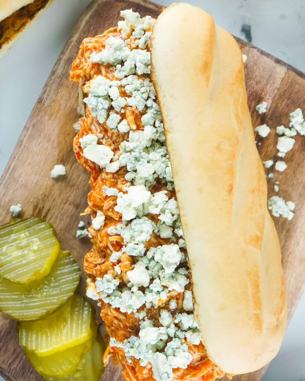 Slow cooker shredded chicken with crumbled blue cheese on hoagie rolls.