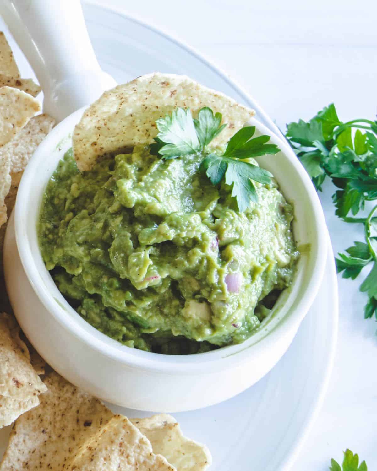 Traditional guacamole recipe in a white bowl. 