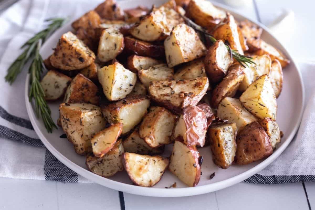 A side view pf a large white plate filled with roasted red potatoes with garlic.  