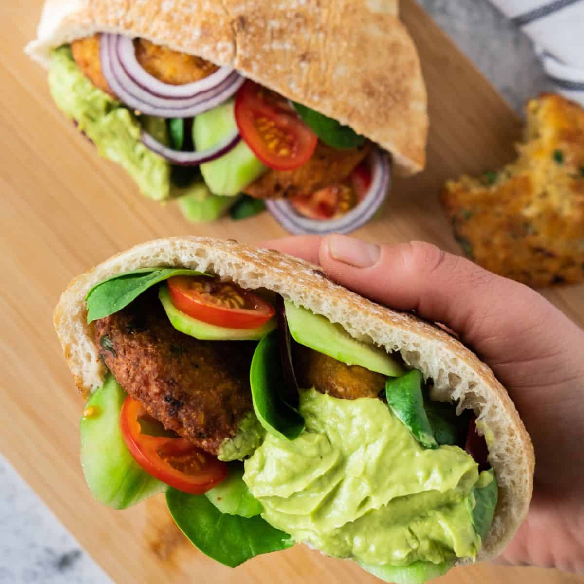 A pita bread filled with falafel balls, sliced tomatoes, red onions, and avocado cream.