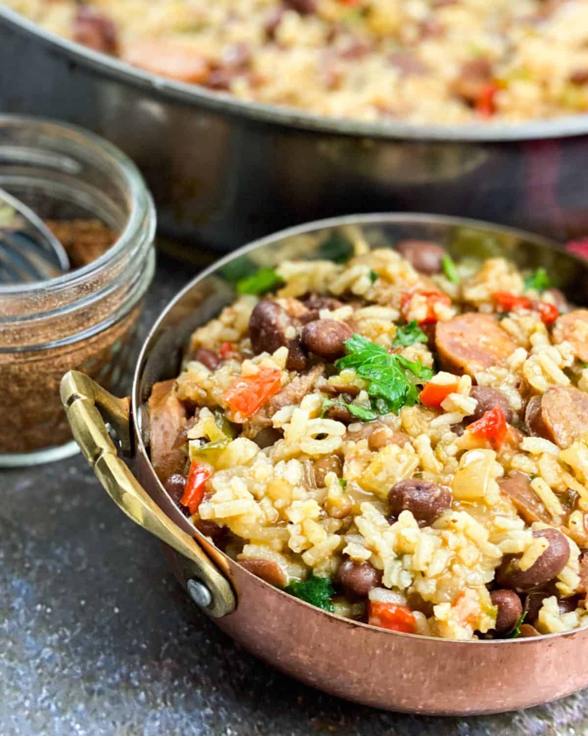 A bowl with handles filled with red beans, rice, and andouille sausage.