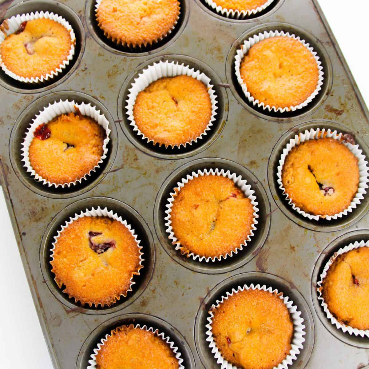 Baked Vanilla Cupcakes in a muffin tin that have a cherry pie filling.  