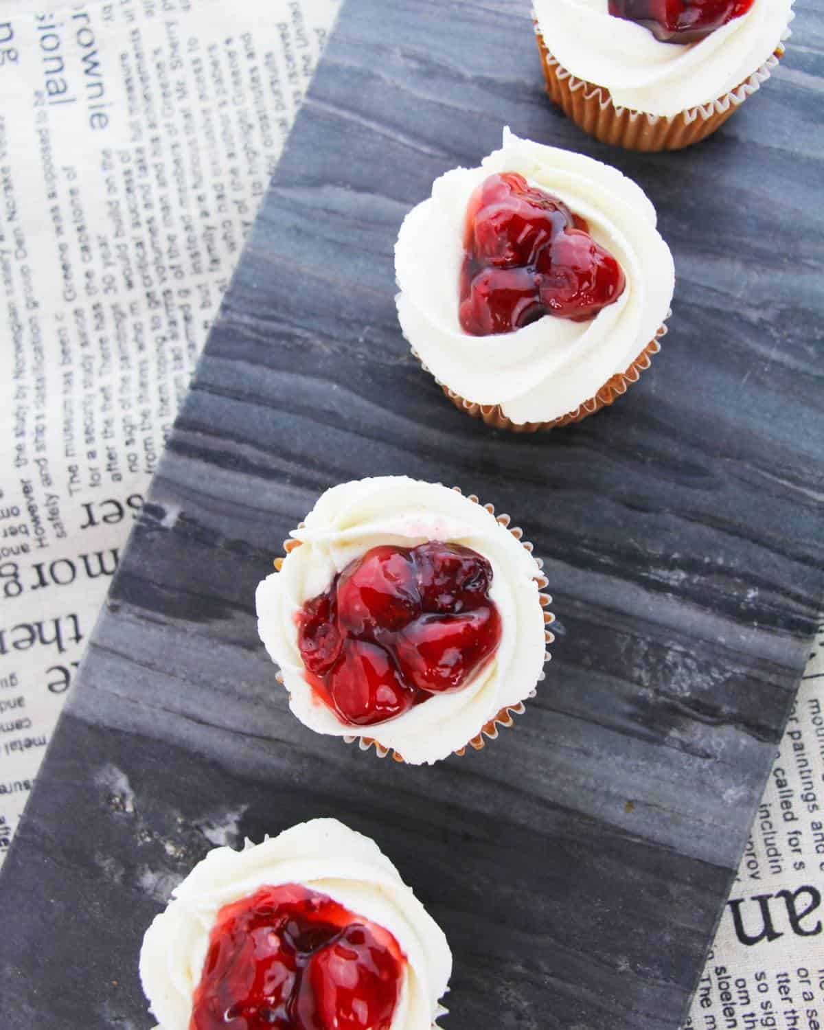 A black slate with cherry pie filled cupcakes on the slate.