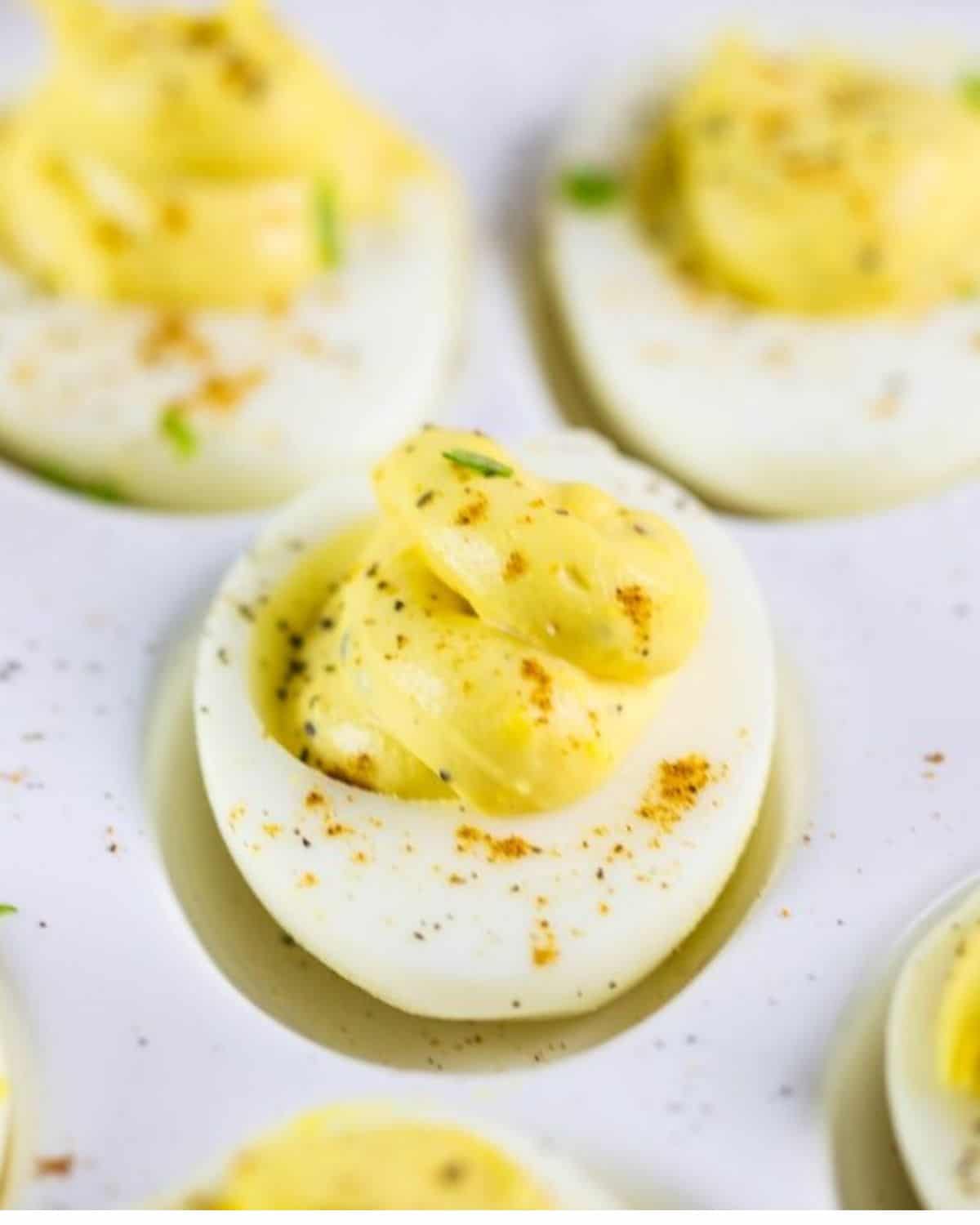 A deviled egg platter with four decorated eggs on the plate. 