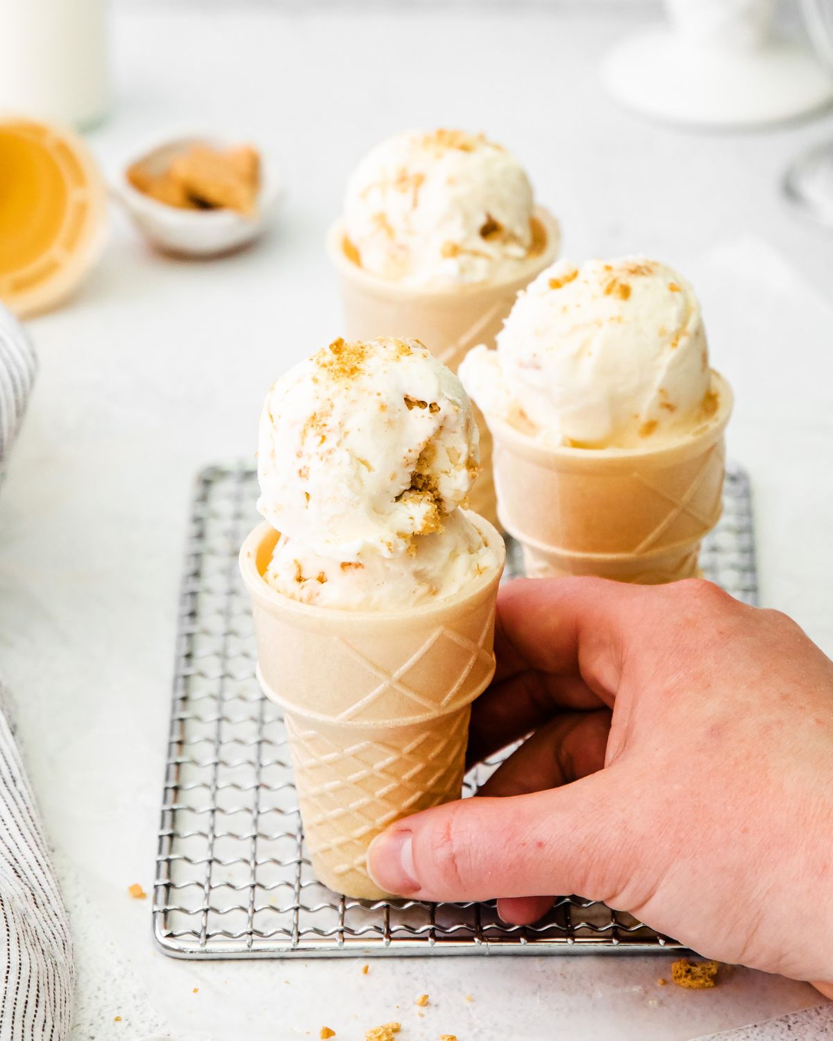 Ice cream cones with cheesecake ice cream being picked up.