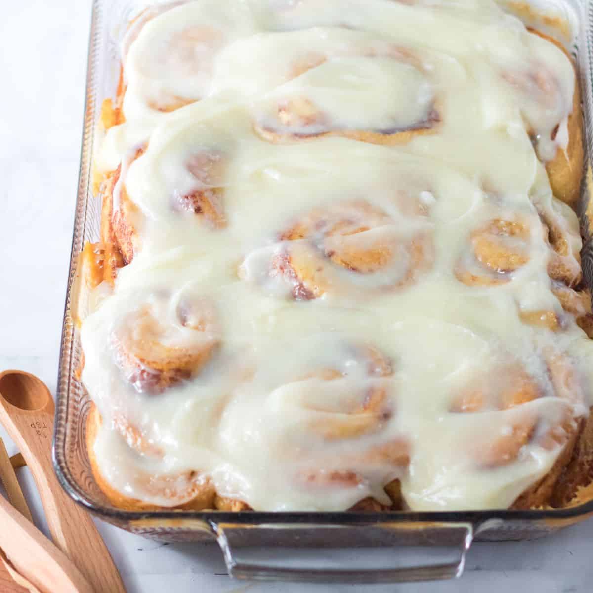 A casserole filled with warm baked cinnamon rolls topped with frosting.