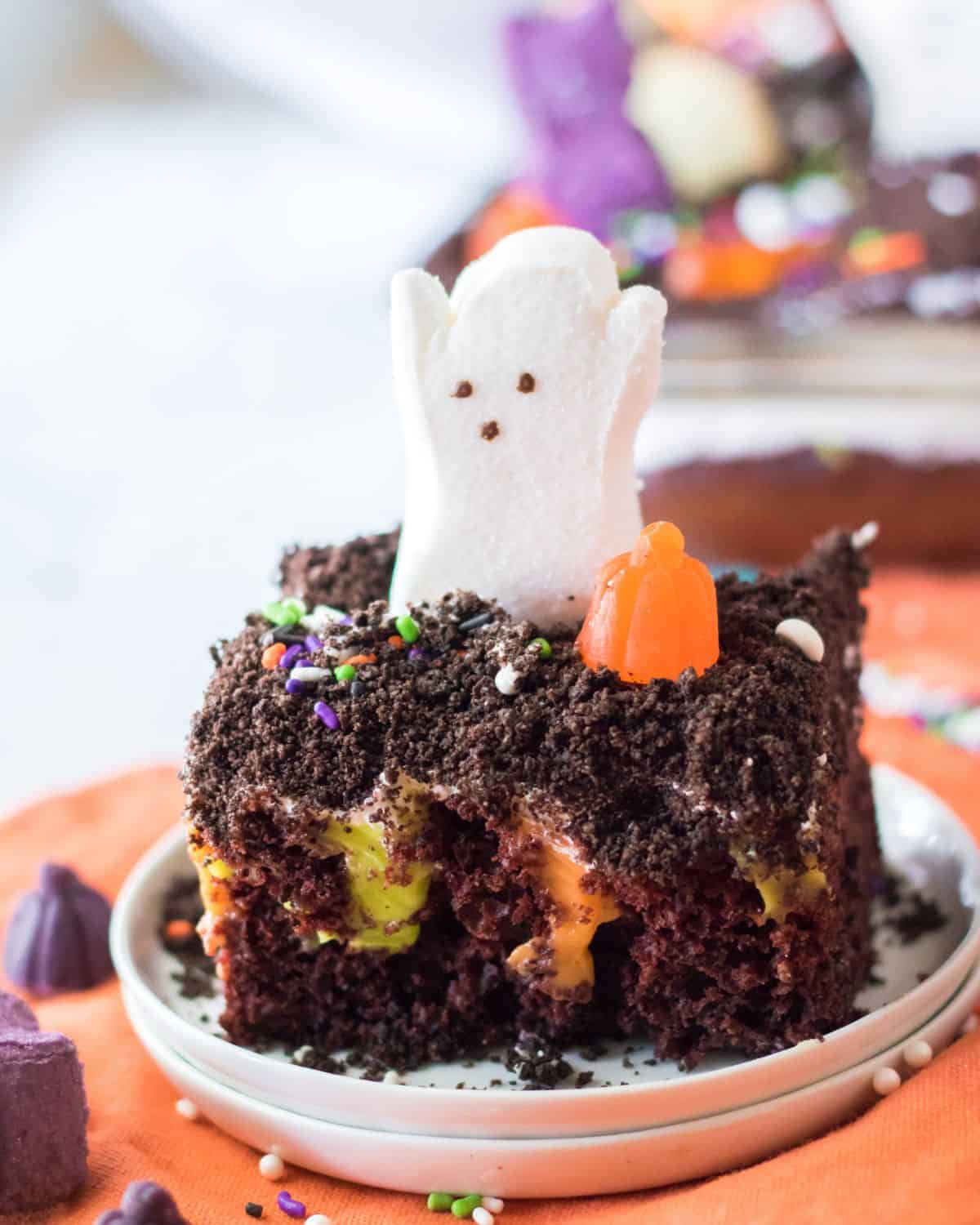 a slice of chocolate cake with orange filling topped with a decorated ghost. 