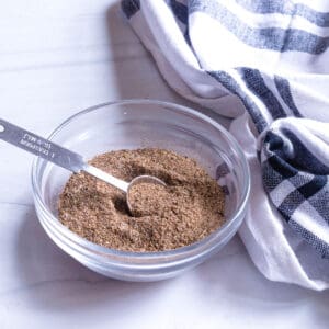 A clear glass bowl with spices to rub on chicken.