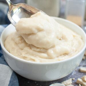 A white bowl with creamy condensed cream of chicken soup in the bowl with a spoon taking some of the soup out.