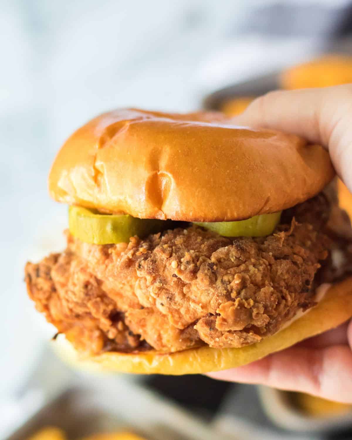 A brioche bun with crispy chicken sandwich being held in a hand.