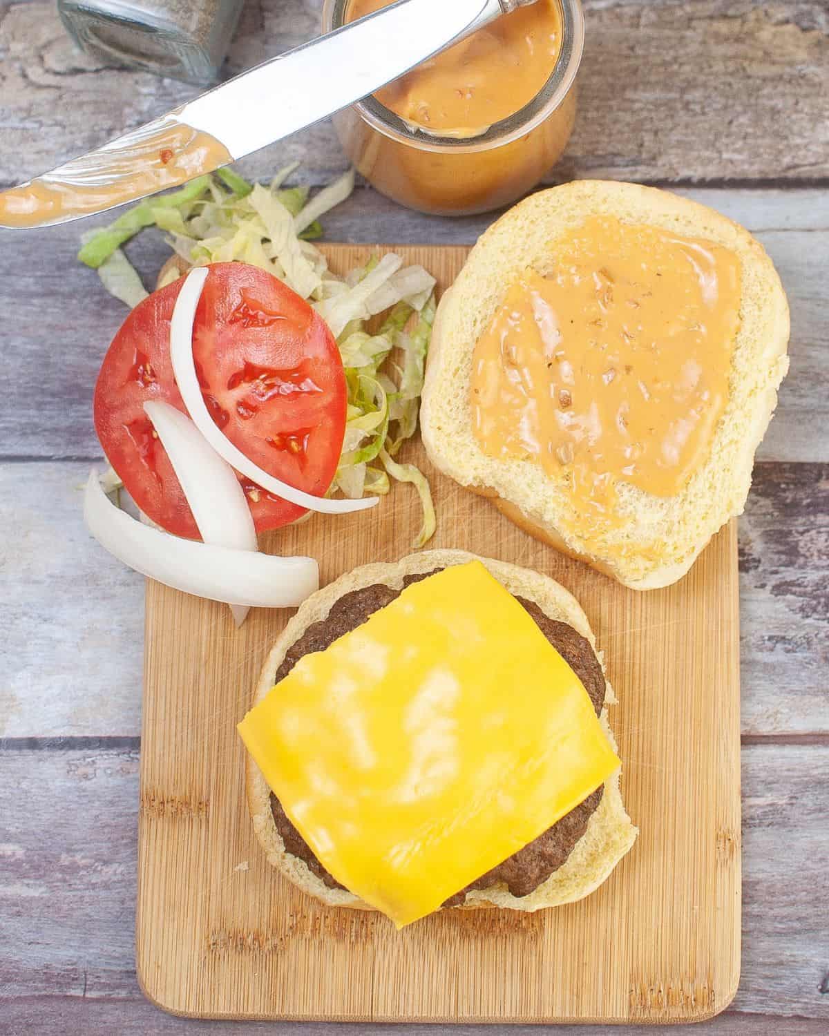 A hamburger topped wit cheese and a bun with a tomato. 