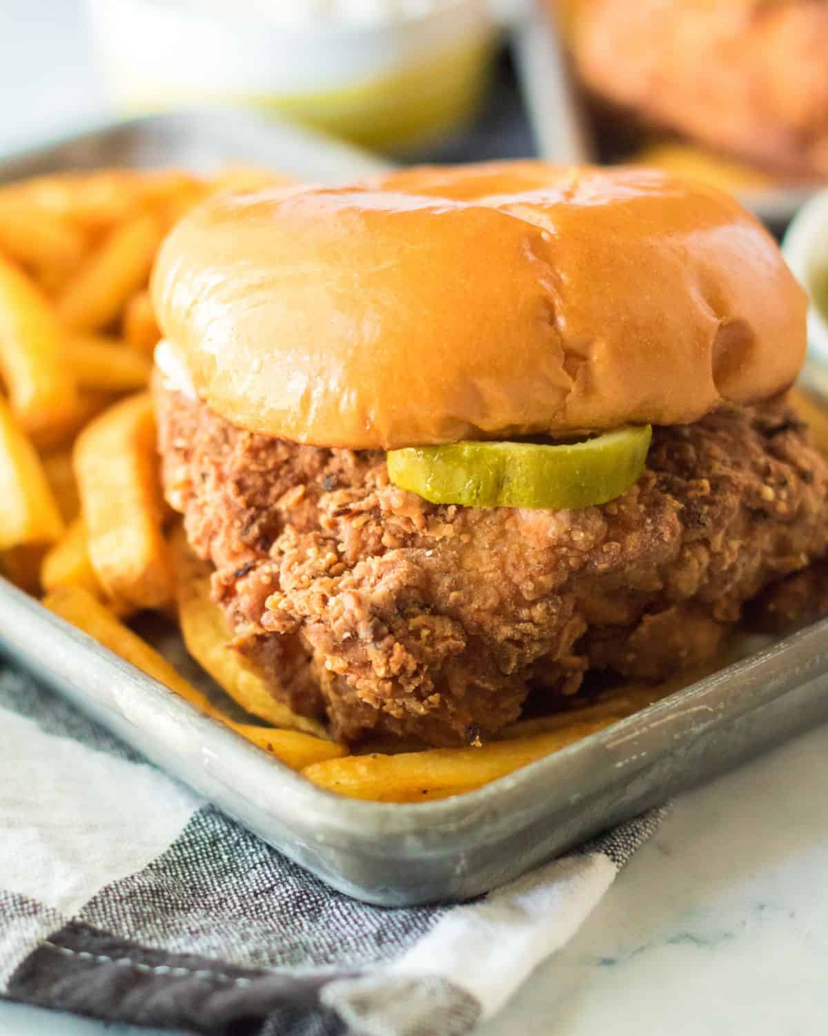 A silver tray with a fried chicken sandwich on the tray.