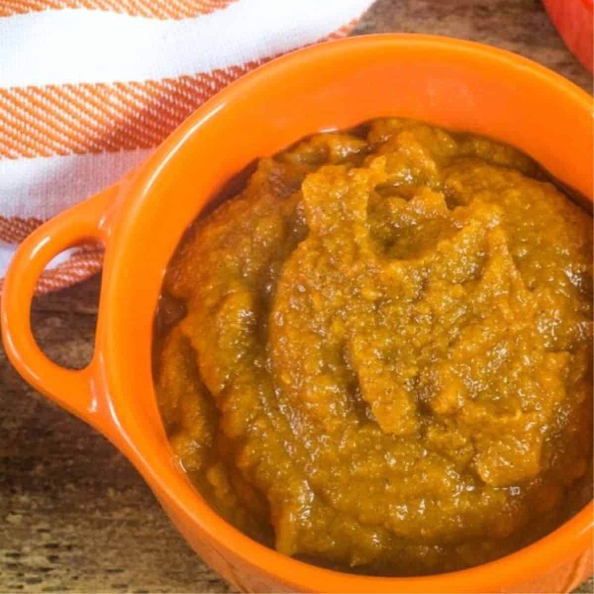 An orange bowl with pumpkin butter in it.