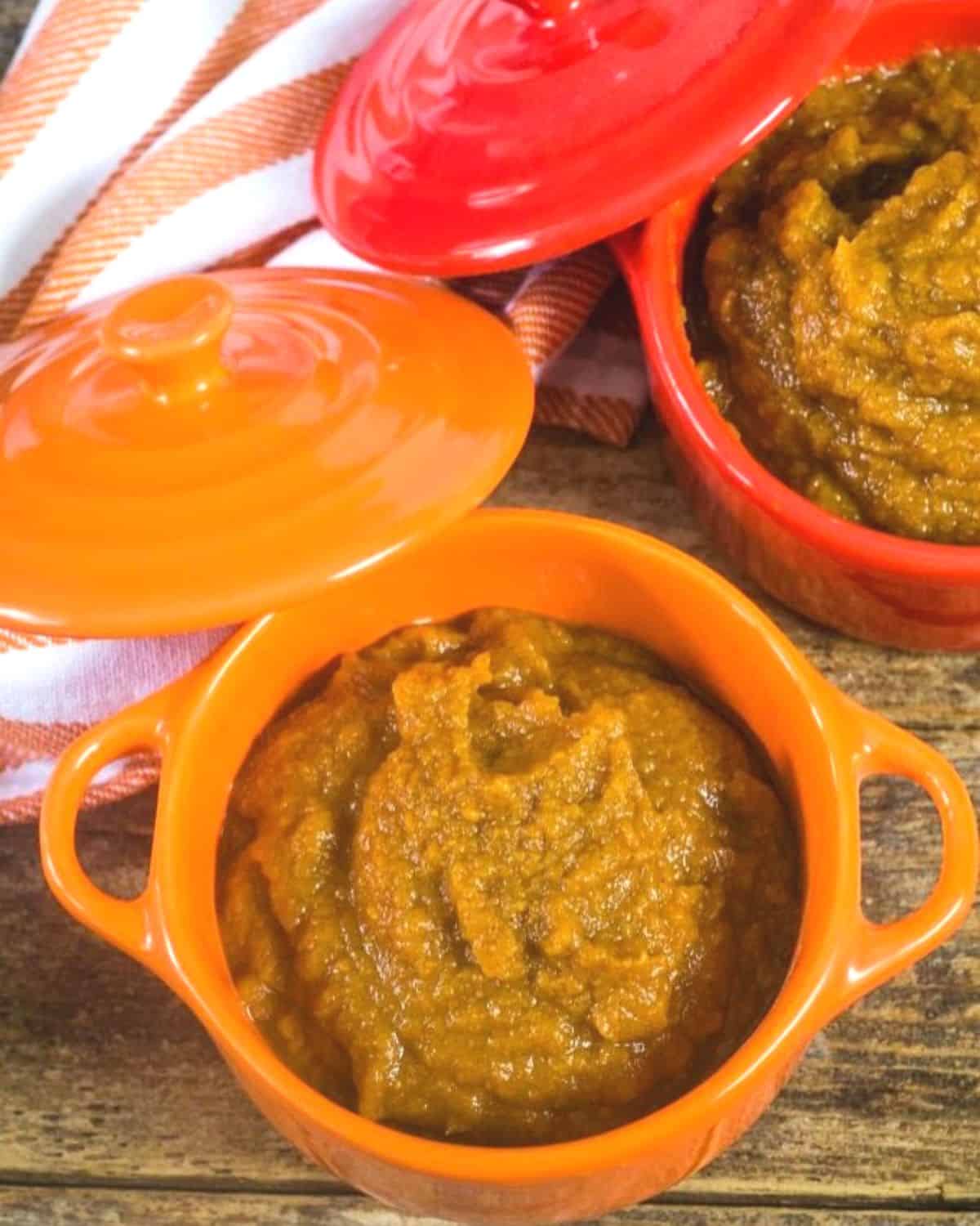 An overhead view of an orange and red crock both filled with pumpkin butter.