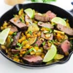 A cast iron skillet with steak and veggies in Southwestern flavors.