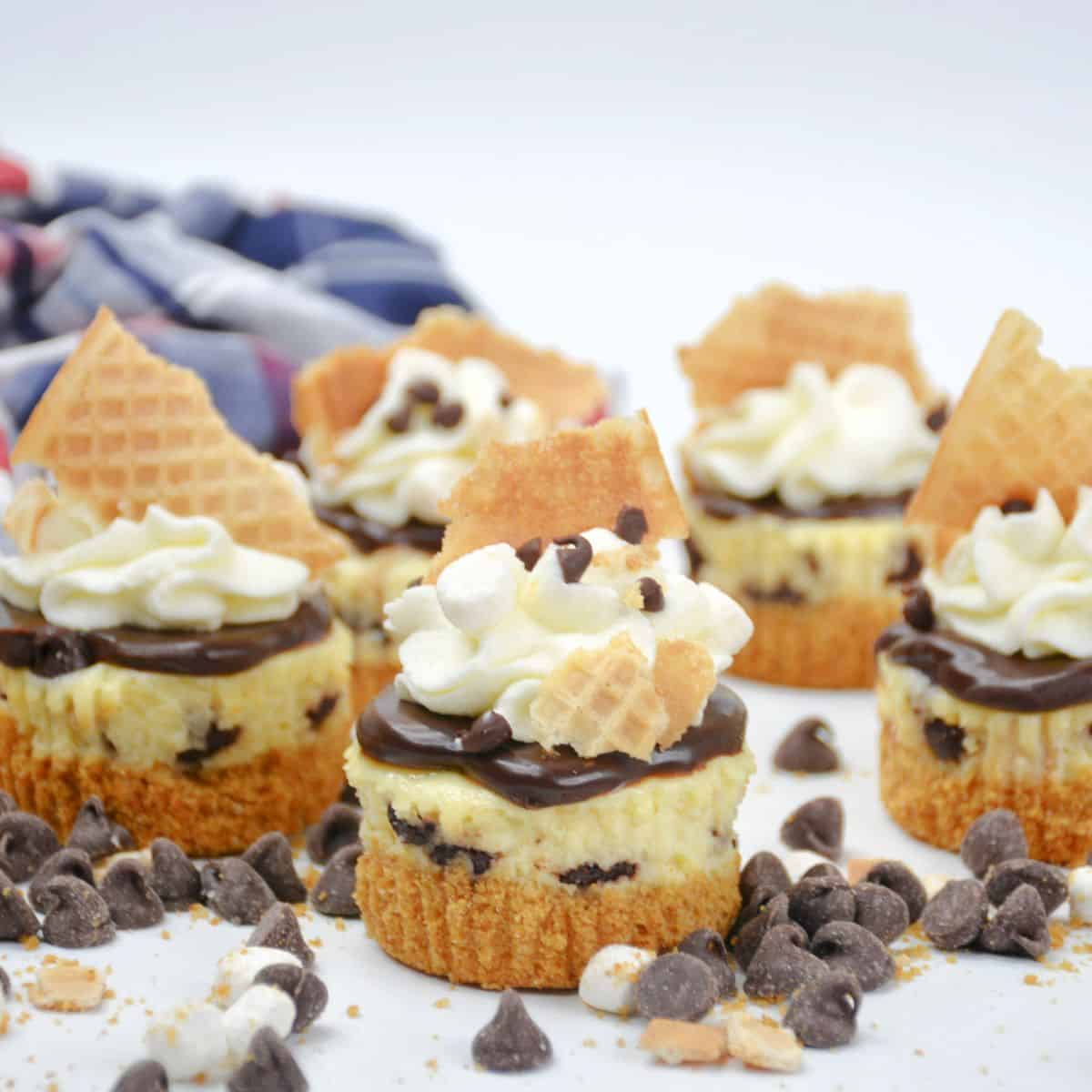 Individual cheesecakes that are flavored as ice cream sundaes topped with marshmallows and chocolate chips. 