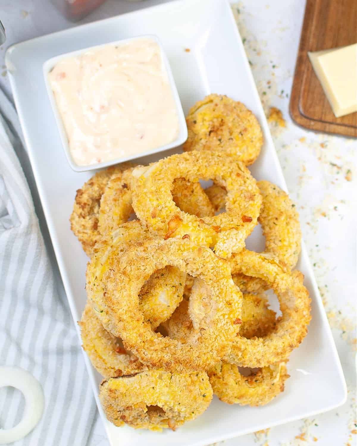 An overhead view of onion rings and dipping sauce that have been air fried and stuffed with cheese.